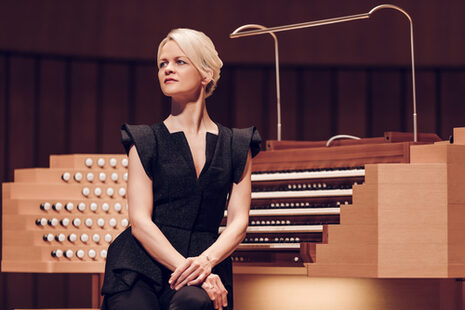 Une femme en robe noire est assise devant une table d'orgue